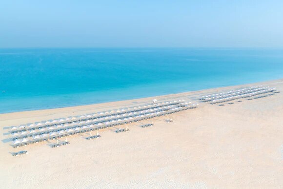 Aerial view of neat rows of parasols on a white-sand beach