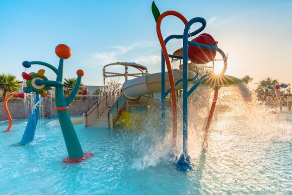 Water park play structure spraying water at sunset